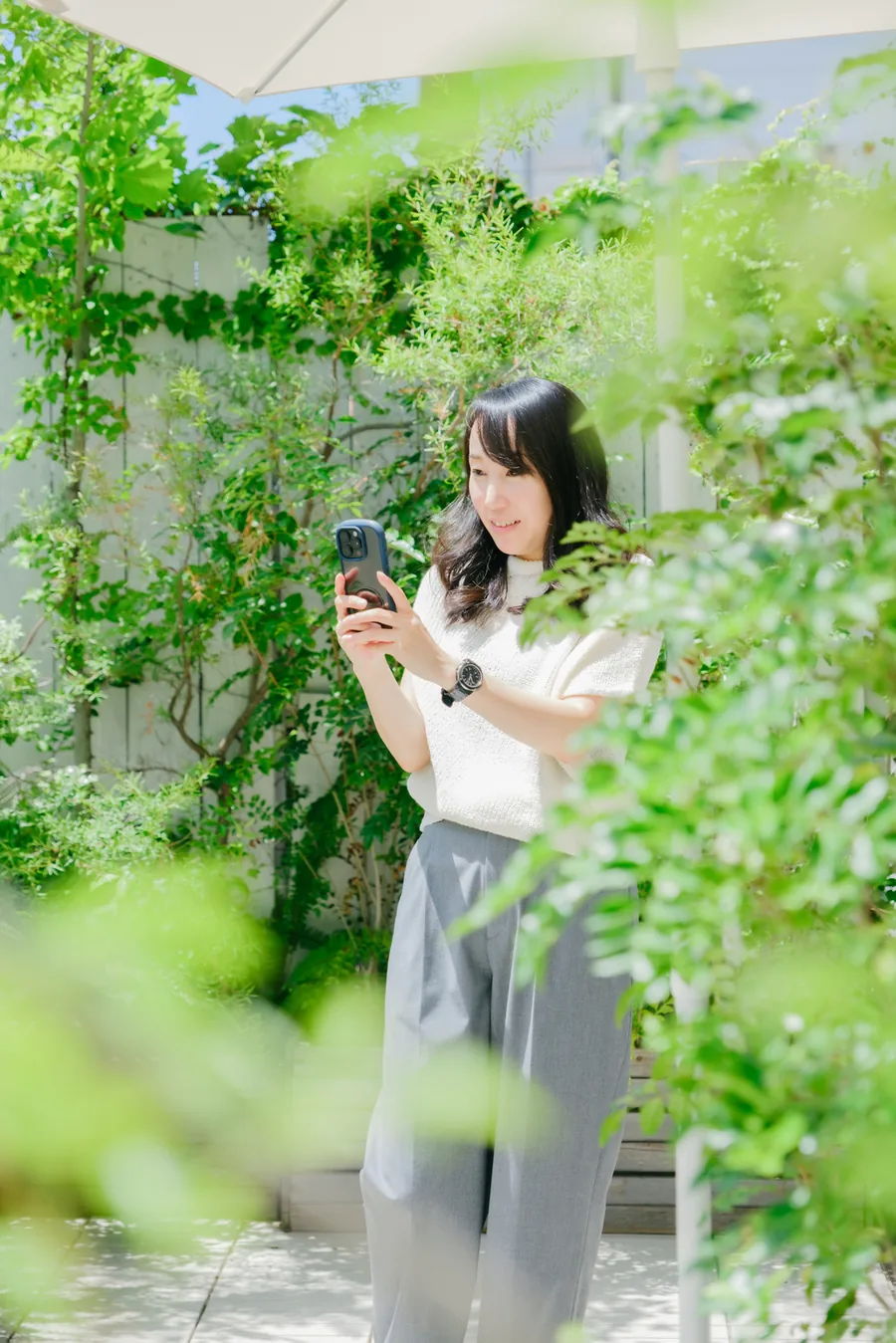 緑の中で、スマホで撮影しているたかこ