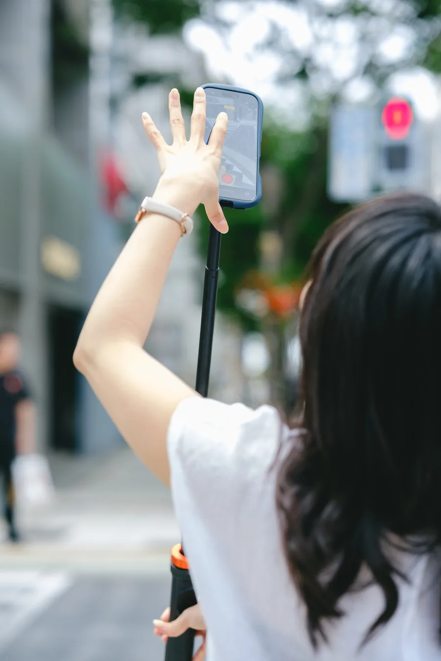 自撮り棒を使って街で撮影している後ろ姿
